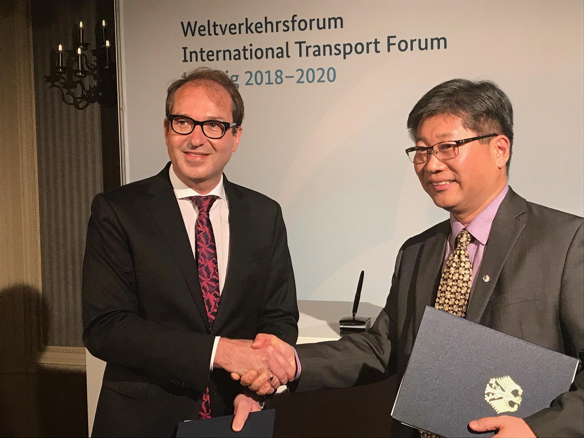 Alexander Dobrindt and Young Tae Kim shalke hands after siging t a gant agreement to hold the Annual Summit of the International Transport Forum in Germany from 2018 through 2020
